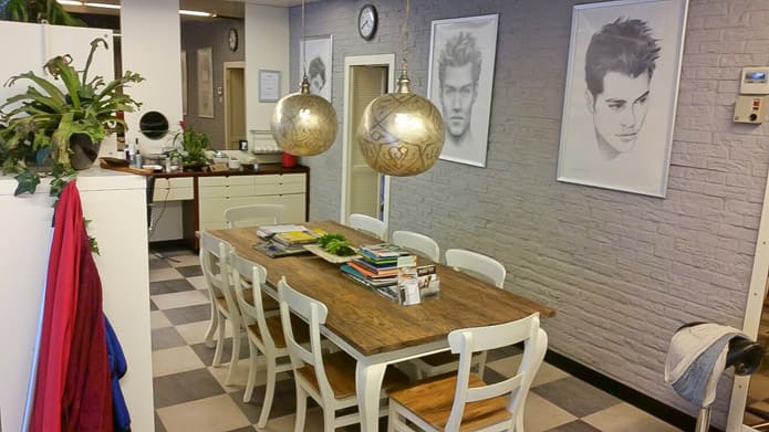 Interieur van Herenkapsalon G. Bouwman, met de wachtplek aan de houten tafel.